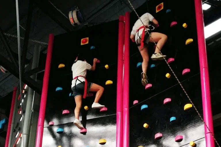 2 Team Members climbing up an indoor rock climbing wall